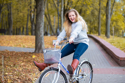 Young beautiful woman rides a bicycle in the autumn park.
