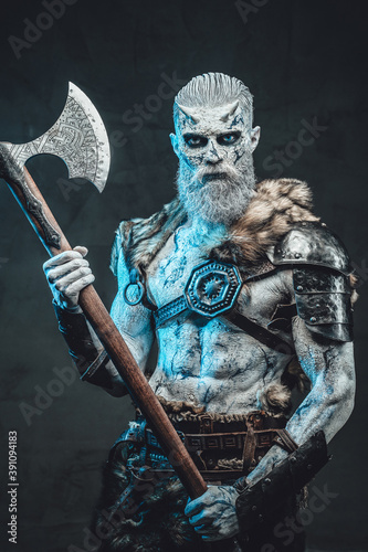 Winter undead warrior with pale skin and blue eyes dressed in armour with fur holding two handed axe in moonlight.