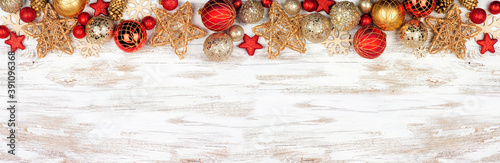 Christmas top border of red and gold ornaments. Overhead view on a white rustic white wood banner background. Copy space.
