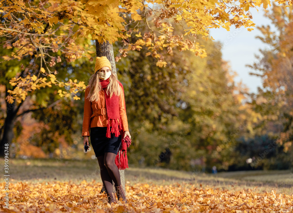 Worried woman checking her phone wearing mask in fall Worried woman checking her phone wearing mask in fall