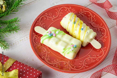 Mousse cake on red plate with fir branches and gift. Christmas background.