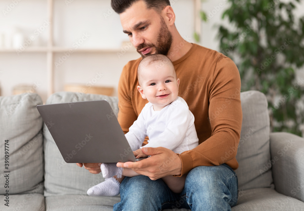 Dad With Baby Working On Laptop Sitting On Couch Indoor Dad With Baby Working On Laptop Sitting On Couch Indoor