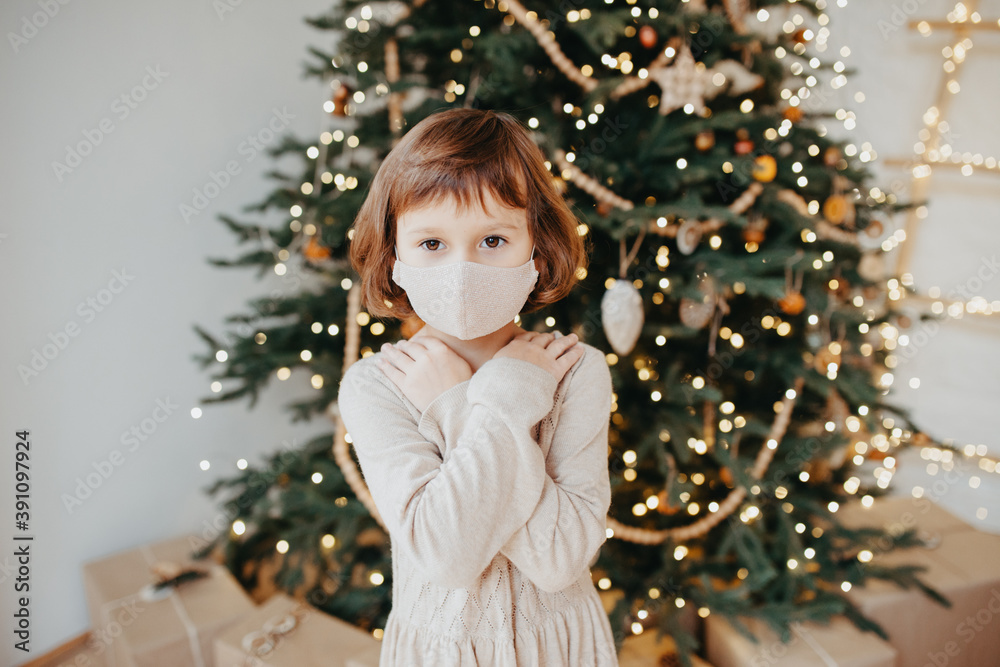 girl meet Christmas in the covid-19 pandemic. Child in protective medical mask