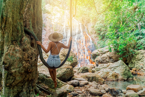 Beautiful Girl sitting at a waterfall in the jungle of Thailand. Exotic tourism in Southeast Asia. Tourist destination Thailand, Koh Samui. 