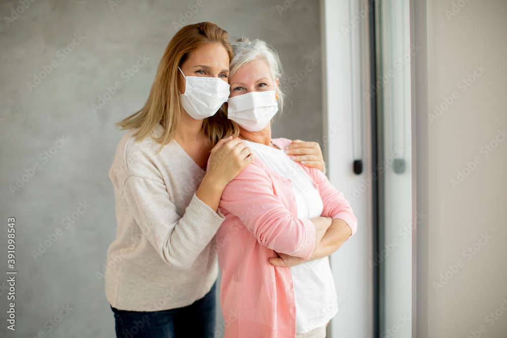 Senior woman with caring daughter at home wearing medical masks Senior woman with caring daughter at home wearing medical masks