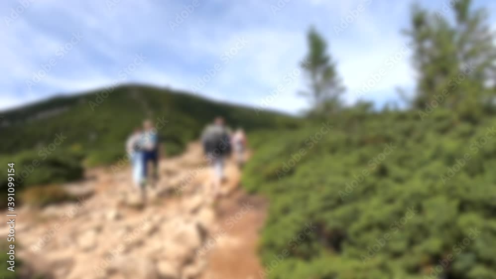 Blurred background. People walk on dirt mountain trail while hiking in mountains Blurred background. People walk on dirt mountain trail while hiking in mountains