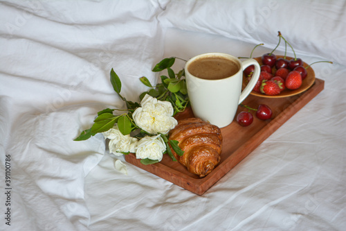Breakfast in bed. Good morning. Wooden tray with a cup of coffee, croissant, berries.