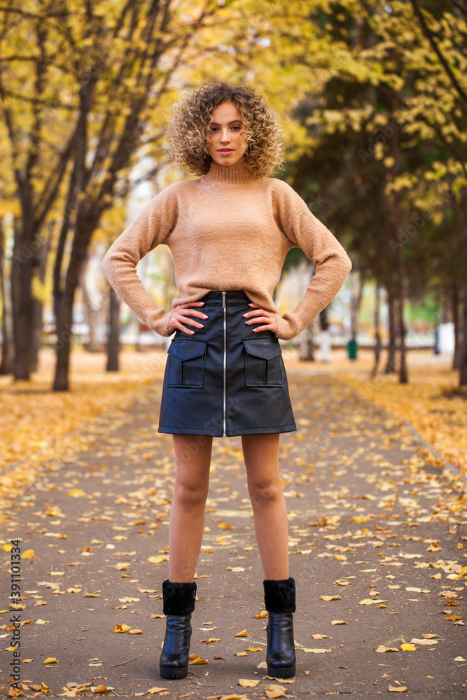 Obraz premium Portrait of a young beautiful girl in beige sweater and black skirt