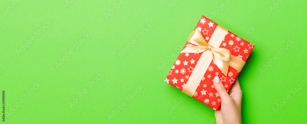 Top view of female hands holding christmas or other holiday handmade present box package in the palms, flat lay table background with copy space Top view of female hands holding christmas or other holiday handmade present box package in the palms, flat lay table background with copy space