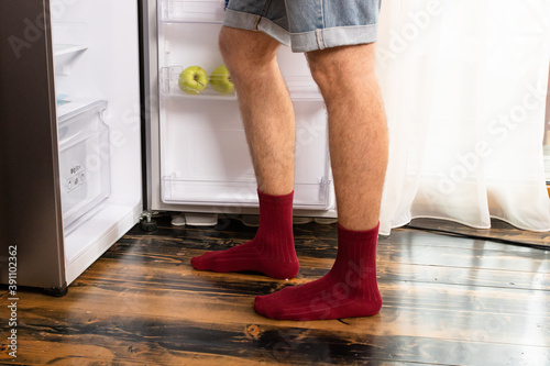 The guy opened an empty refrigerator, his legs close up.