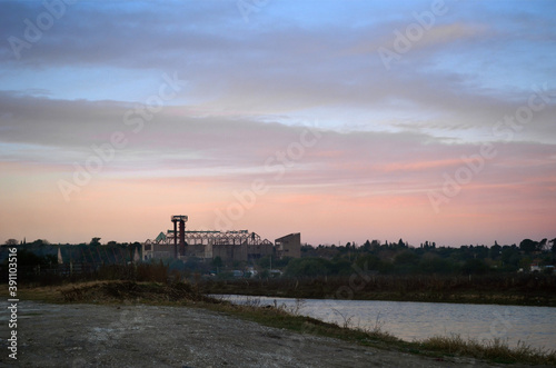 Antigua fábrica abandonada desde la costa al atardecer. © ameaz_23