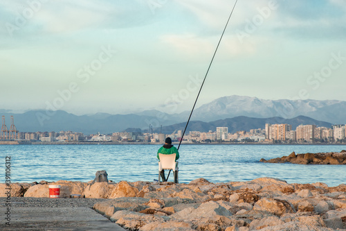 Fisherman on the beach - Fisherman sitting on the coast line with Malaga city in its background - Fishing on the beach 