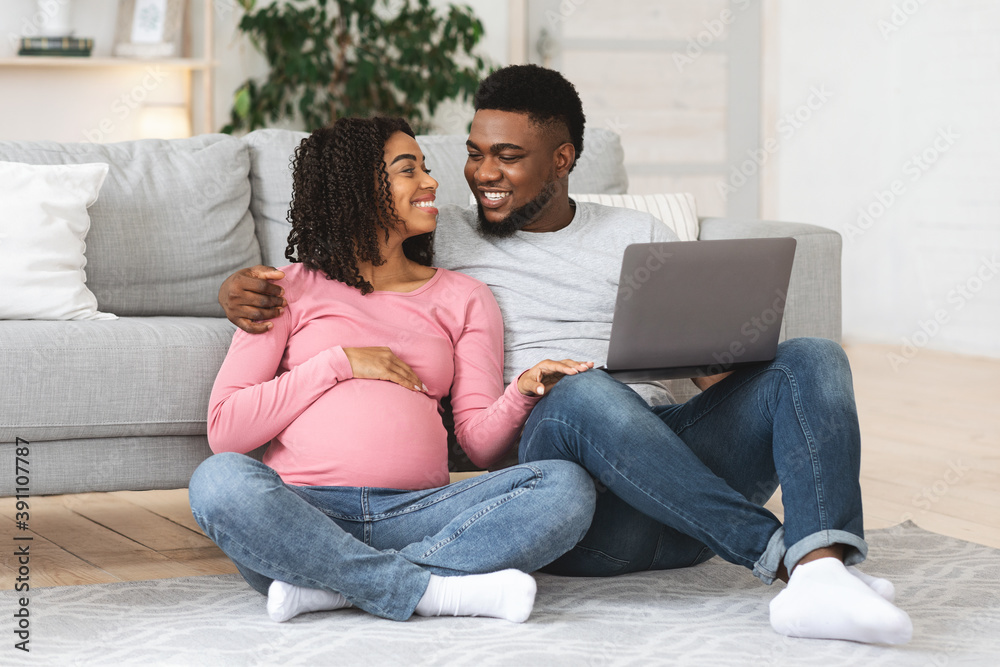 Loving pregnant black couple using laptop at home Loving pregnant black couple using laptop at home