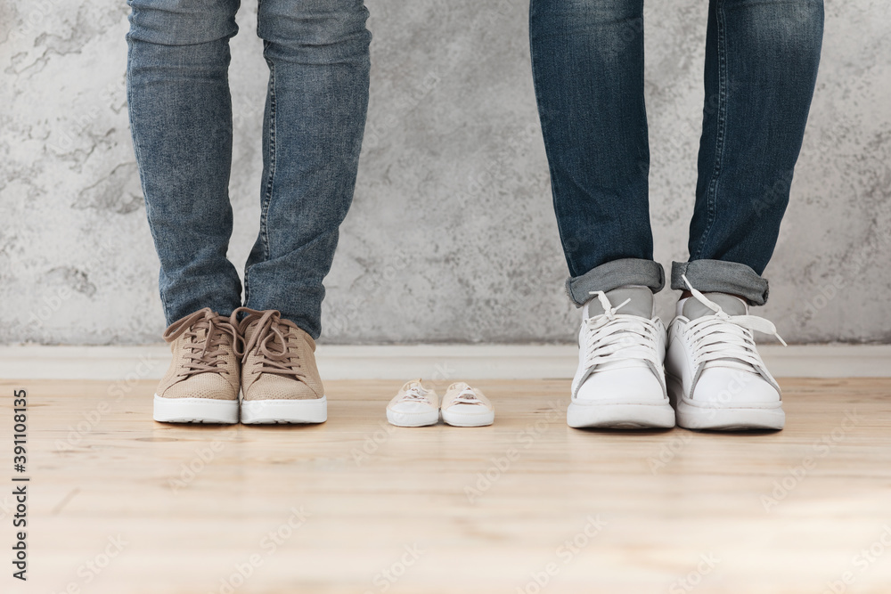 Man and woman standing next to small baby shoes Man and woman standing next to small baby shoes