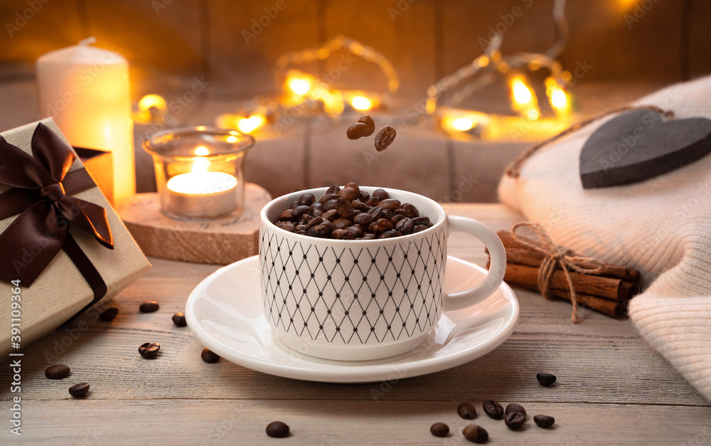 Coffee beans in a Cup and hanging in the air above the Cup on a cozy festive background. Concept of coffee and holidays. Coffee beans in a Cup and hanging in the air above the Cup on a cozy festive background. Concept of coffee and holidays.