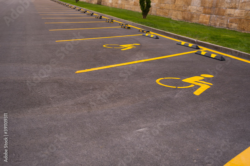 car parking area for people with disabilities. yellow handicapped sign on black asphalt area, road signs, markings on the road.