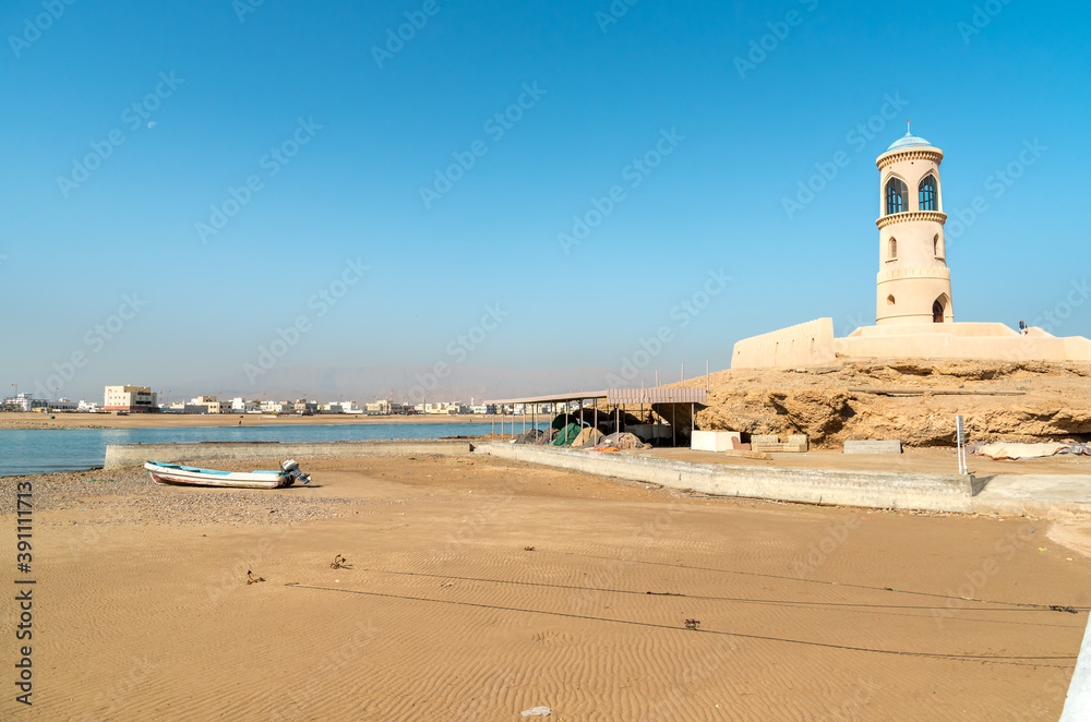 View of Al Ayjah Lighthouse with fish boat on the beach in Sur, Sultanate of Oman.