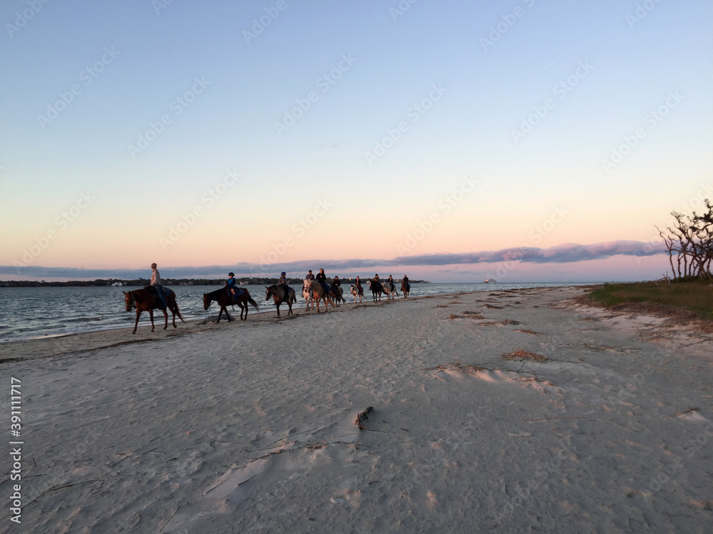 people riding horses at sunset on the beach people riding horses at sunset on the beach
