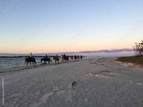 people riding horses at sunset on the beach