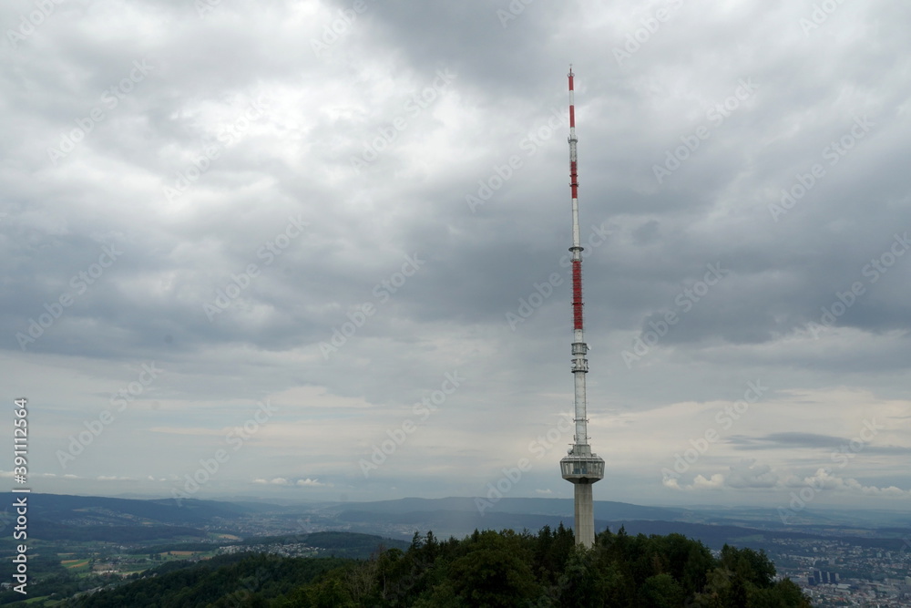 Obraz premium Telecommunication signal emitter or antenna for broadcasting on high placed Uetliberg mountain above Zurich in Switzerland. Summer landscape on on a cloudy rainy day with dramatic sky.