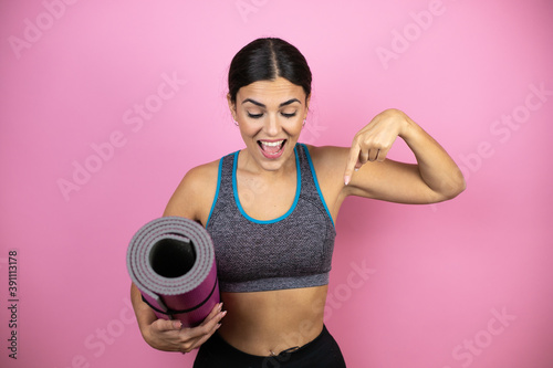 Young beautiful woman wearing sportswear over isolated pink background pointing finger down surprised.