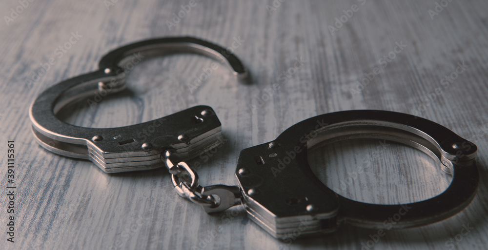 Isolated handcuffs, banner and copy space on a wooden background.