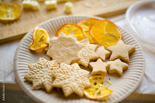 white plate with delicious fresh pastries. cookies in the form of stars and an orange on the table. hand made.