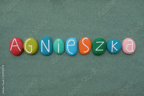 Agnieszka, polish female given name composed with multicolored stone letters over green sand photo