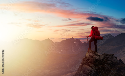 Woman Standing on Rocks looking at Scenic Mountain Peaks and Valley, Fall in Canadian Nature. Dramatic Twilight Sky Adventure Composite. Bacground Landscape, Tombstone Territorial Park, Yukon, Canada.