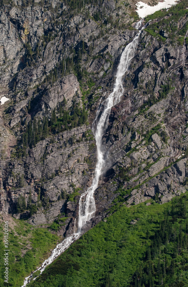 Obraz premium Water falls down mountains in Glacier National Park.