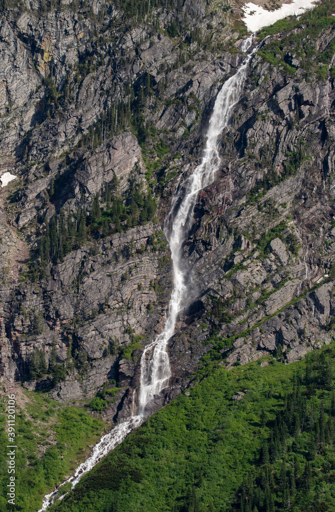 Water falls down mountains in Glacier National Park.
