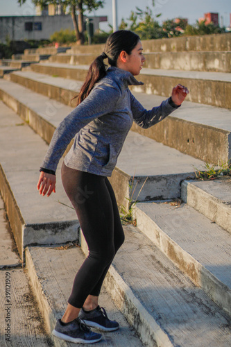 Latin Hispanic woman with black hair doing yoga exercise outdoors in a park