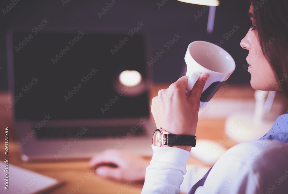 Portrait of relaxed young woman sitting at her desk holding cup of coffee. Business Woman. Workplace