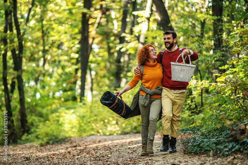 Young happy couple walking in nature. Man is holding basket. Couple is going on picnic.