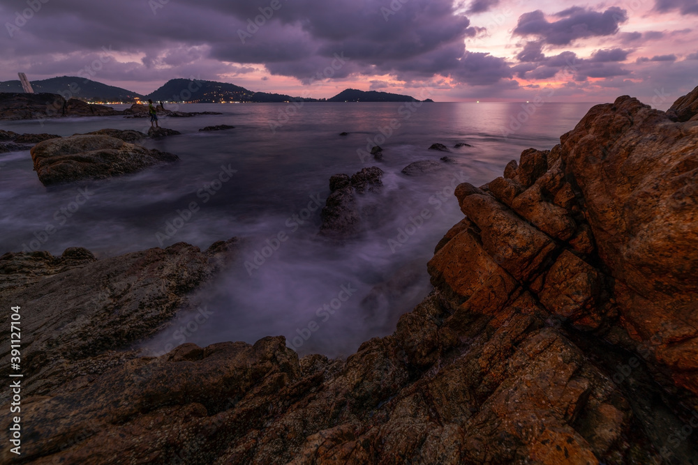Long exposure image of Dramatic sky seascape with rocks in the foreground sunset or sunrise over sea scenery background.