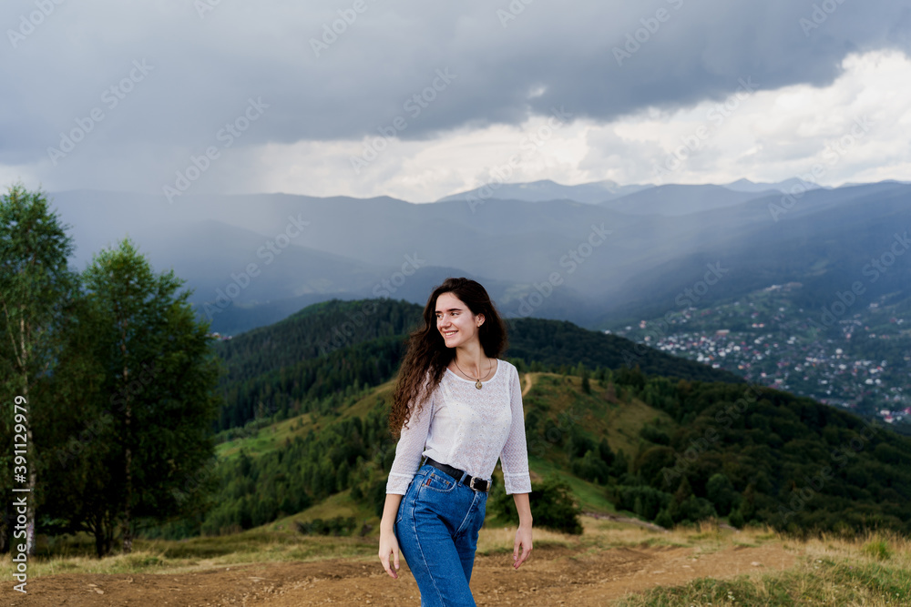 Tourism travelling in Ukraine. Girl enjoying the mountain hills view before rain. Feeling freedom in Karpathian mountains.