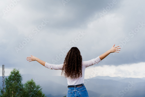 Feeling freedom in Karpathian mountains. Tourism travelling in Ukraine. Girl girl raised her hands up and enjoys the mountain hills view.