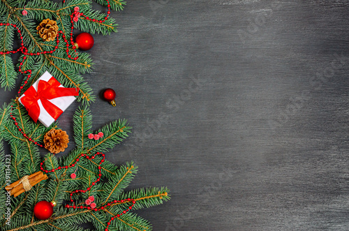 Christmas decorations, gift box, cinnamon, decorative beads, cones and fir branches on a black background.