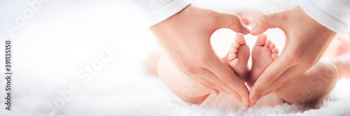 Mother Holding Baby's Feet In Heart Shaped Hands - Infant Care Concept photo