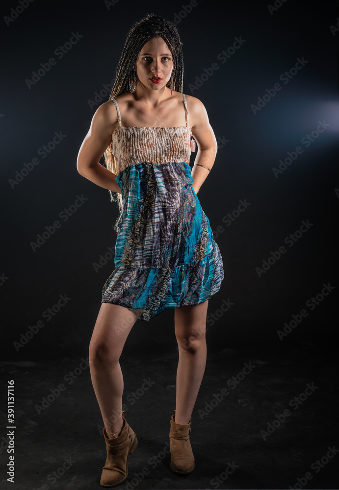  Portrait of a charming girl with braids with a mystic look at the camera. Studio black background..