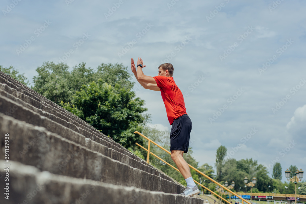 Side view picture of an active male athlete jumping up on stairs in outdoor training. .