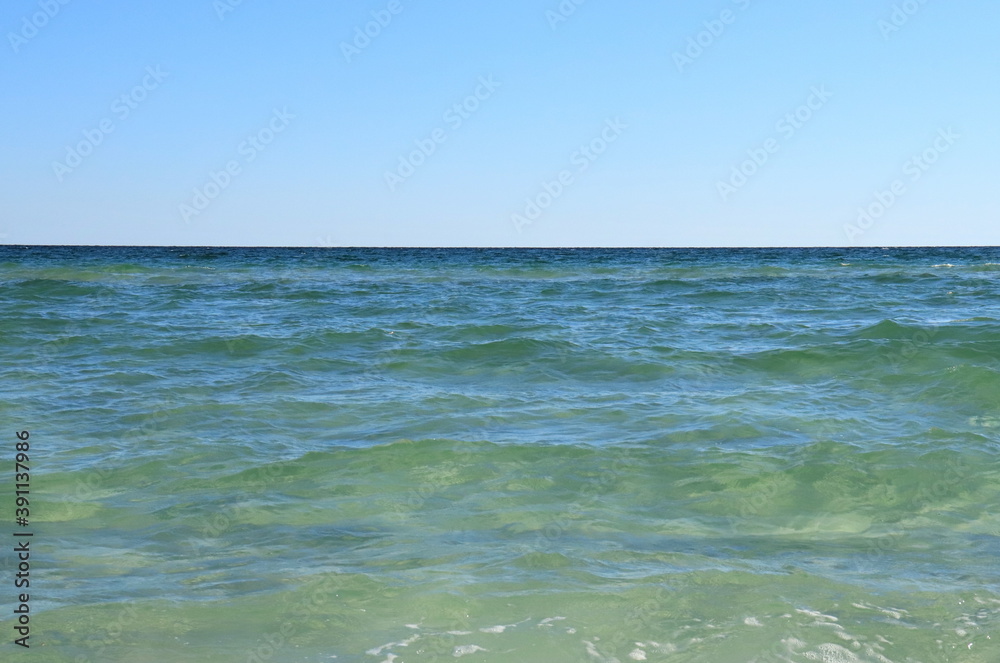 Seascape, green ocean waters, small waves, blue sky above the horizon