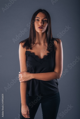 Sensual studio portrait of a sexy woman standing with one arm crossed on a gray background © qunica.com
