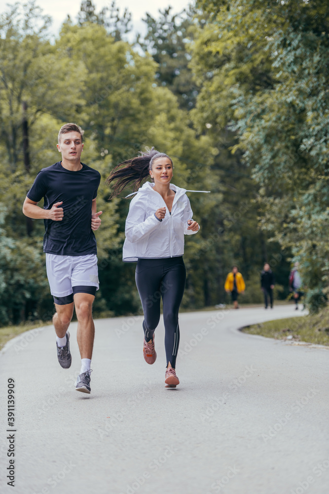 Athletic couple running on a street next to each other. Nature,fit and healthy concept. Athletic couple running on a street next to each other. Nature,fit and healthy concept.