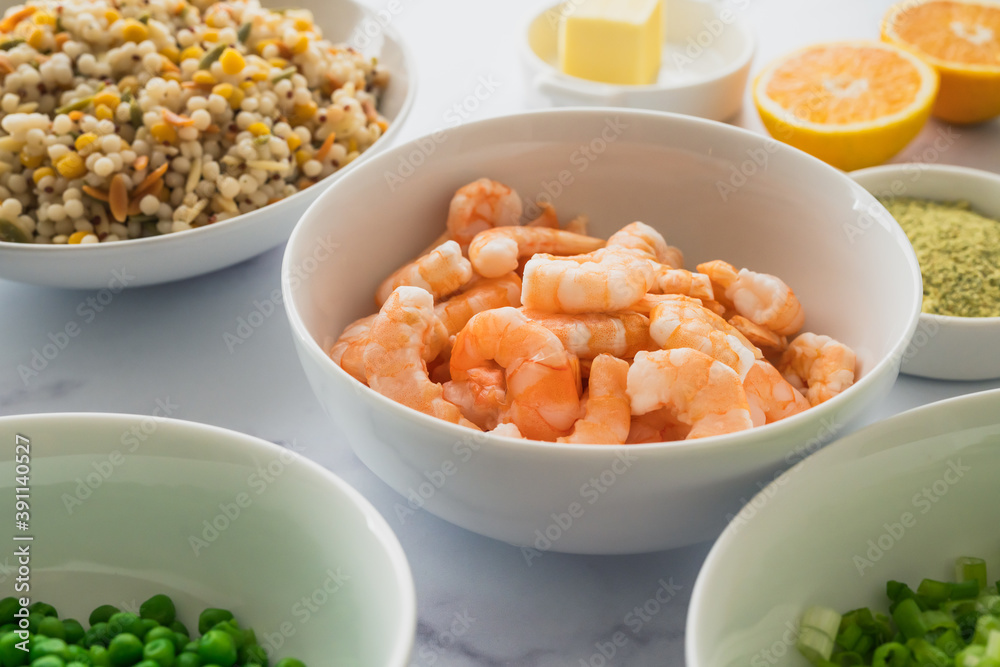 Blend of couscous, orzo, garbanzo beans, and red quinoa, shrimps, green peas, and chopped green onion in bowls close up on marble background Blend of couscous, orzo, garbanzo beans, and red quinoa, shrimps, green peas, and chopped green onion in bowls close up on marble background