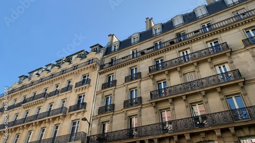 Bottom view footage of historical, traditional buildings showing French architectural style in Paris. It is a sunny summer day. Camera moves forward.