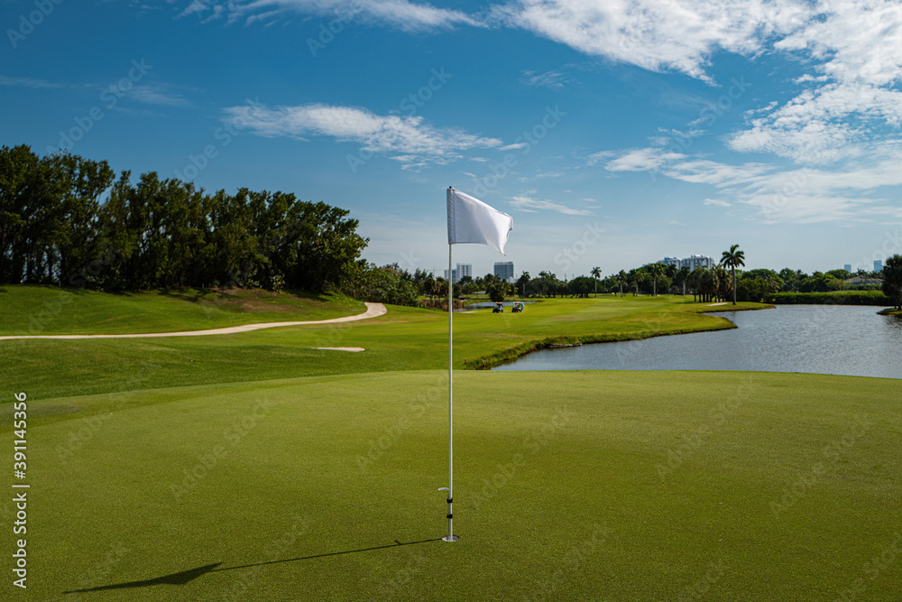 Obraz premium Countryside golf course with flags, greens and sand bunker.