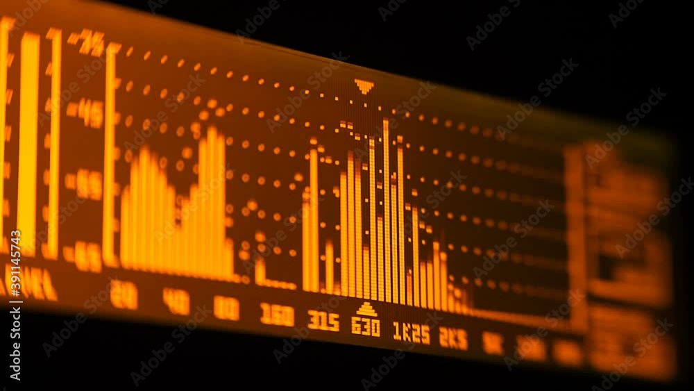 The professional concert equalizer has a yellow spectrum analyzer on the display that analyzes the frequency range of music or any sound and can change it. Closeup