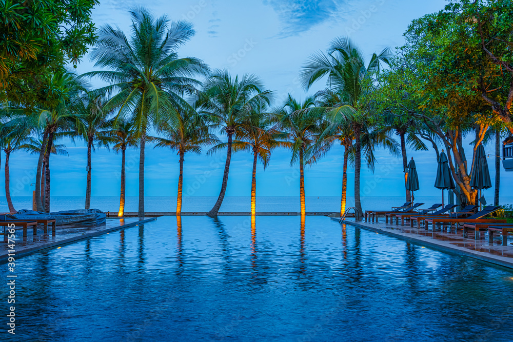  swimming pool with background of coconut tree and sea at beachfront resort
