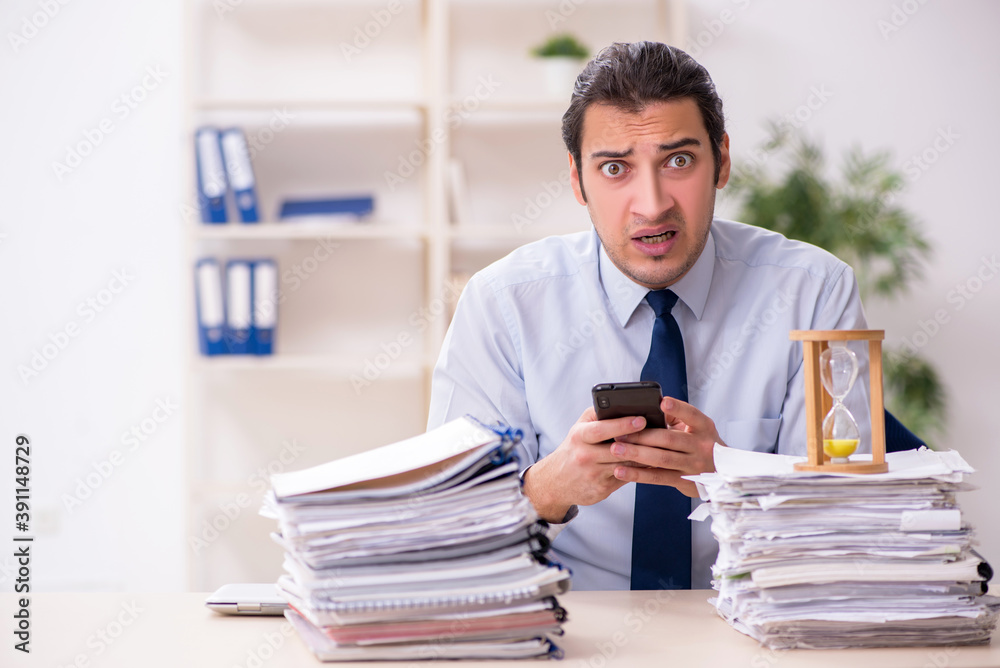 Young male employee in time management concept Young male employee in time management concept